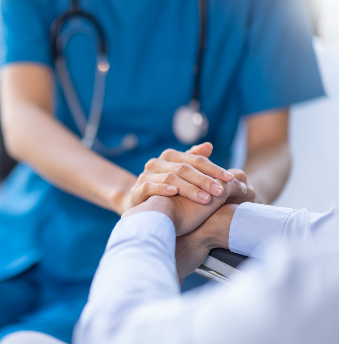 A caregiver comforts patient by holding hands.